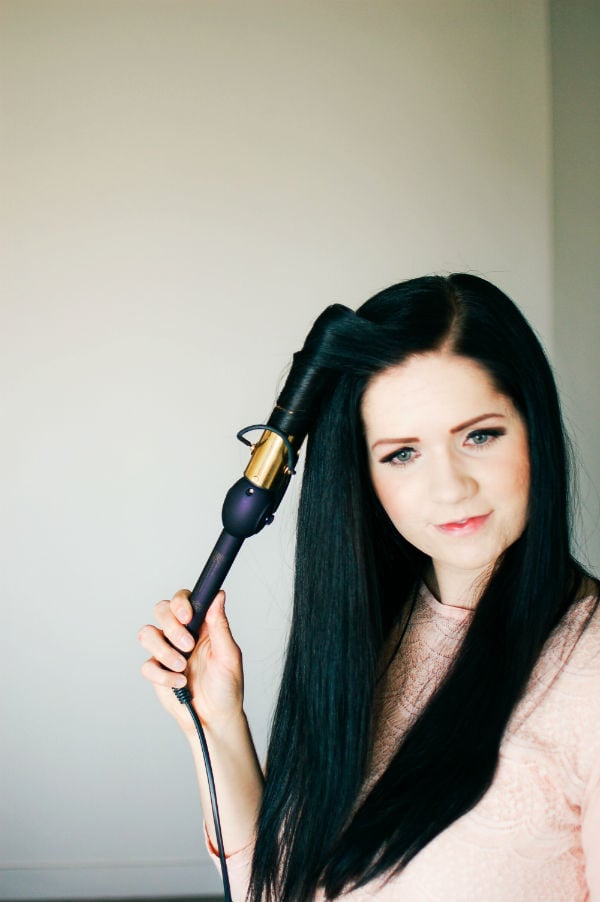 A woman shows her hair curling tutorial for long hair.