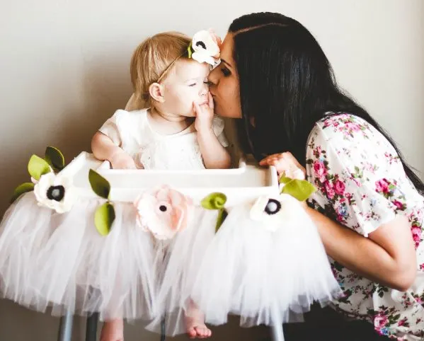 Mom kisses daugther during her floral first birthday party.