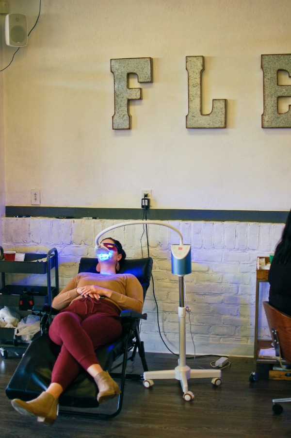 Woman leans back in a chair while getting her teeth whitened with a laser.