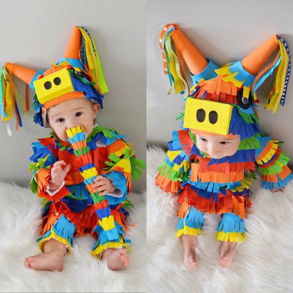 A baby dressed up as a pinata using colorful construction paper as fringe.