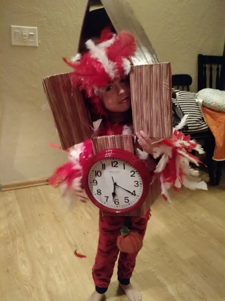Boy wearing DIY cuckoo clock Halloween costume smiles and stands in living room.
