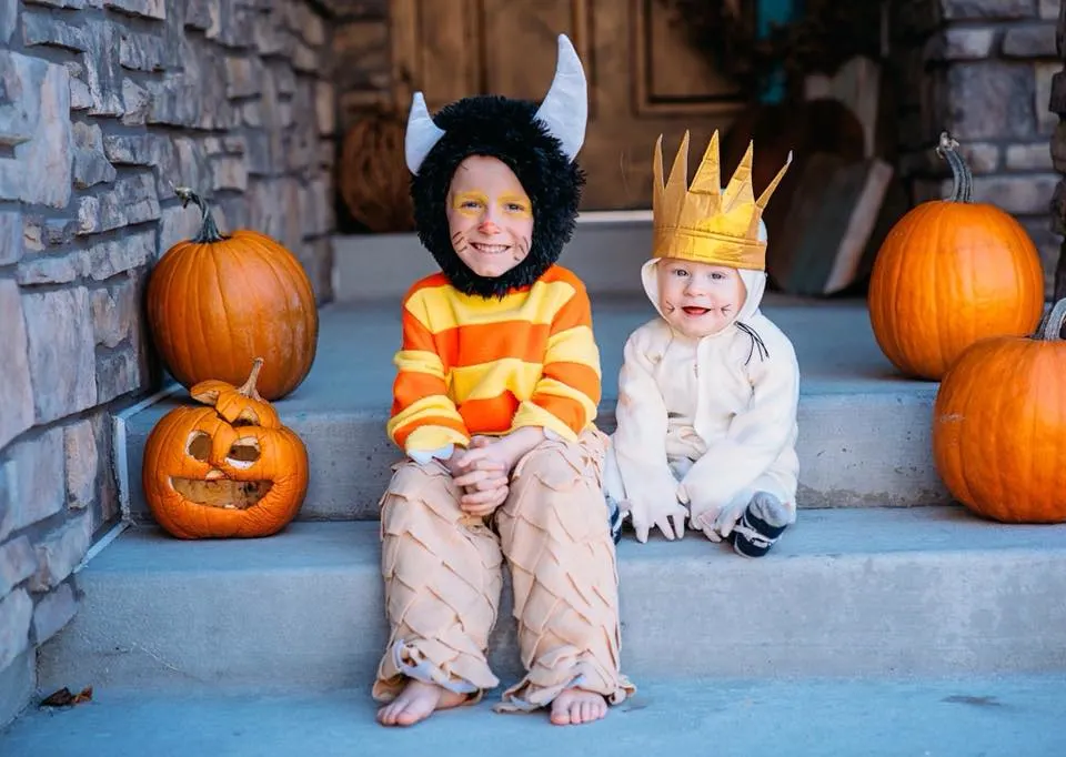 Two boys dressed up in "Where the Wild Things Are" costumes with a monster hat and crown sitting on front steps with jack-o-lanturns.