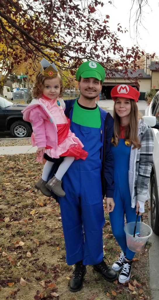 Family wearing Super Mario Halloween costumes smiles in front yard for picture.