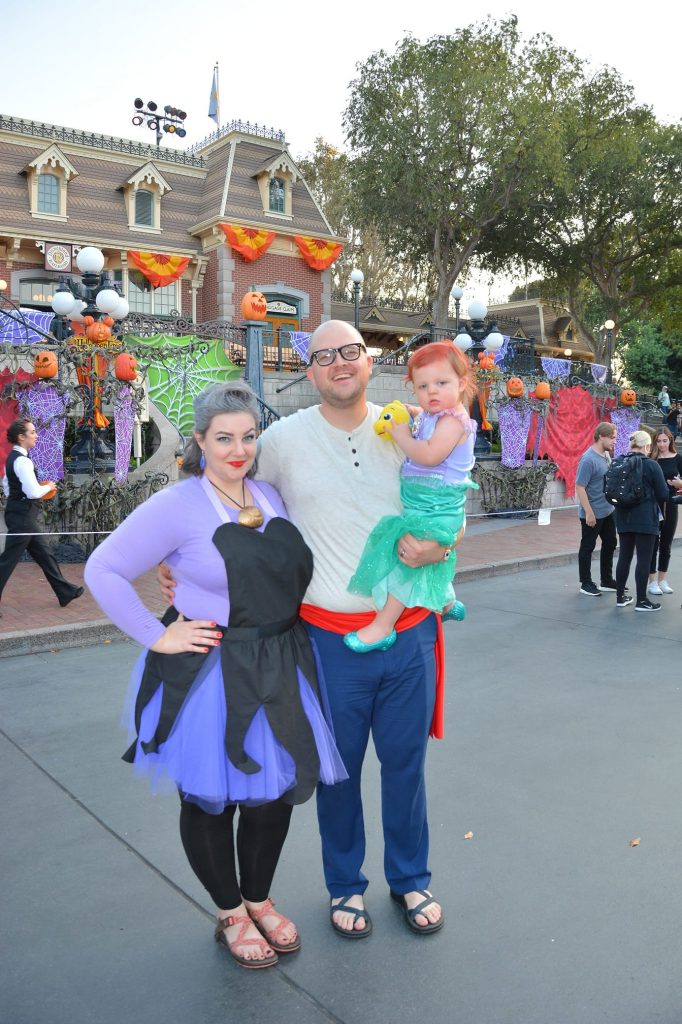Family dresses as characters from Little Mermaid smiles on Disneyland's main street.