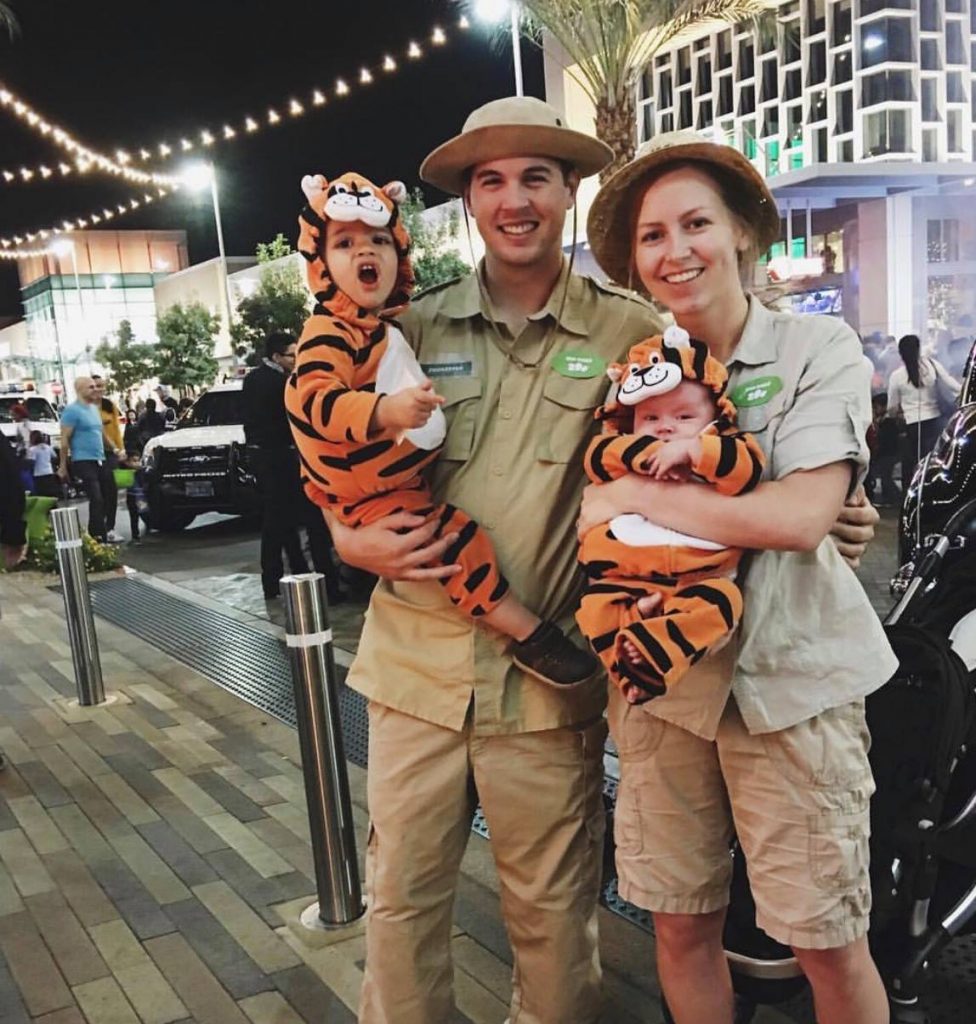 Family wearing zookeeper and animal Halloween costumes poses for picture.