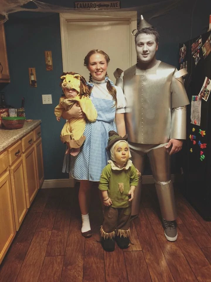 Family wearing Wizard of Oz DIY Halloween costumes smiles in kitchen.