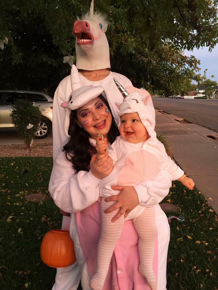 Family wearing unicorn Halloween costumes poses for picture in front yard.
