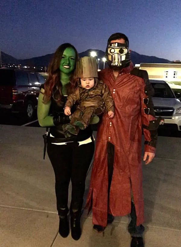 Family wearing Guardians of the Galaxy Halloween costumes smiles in parking lot.