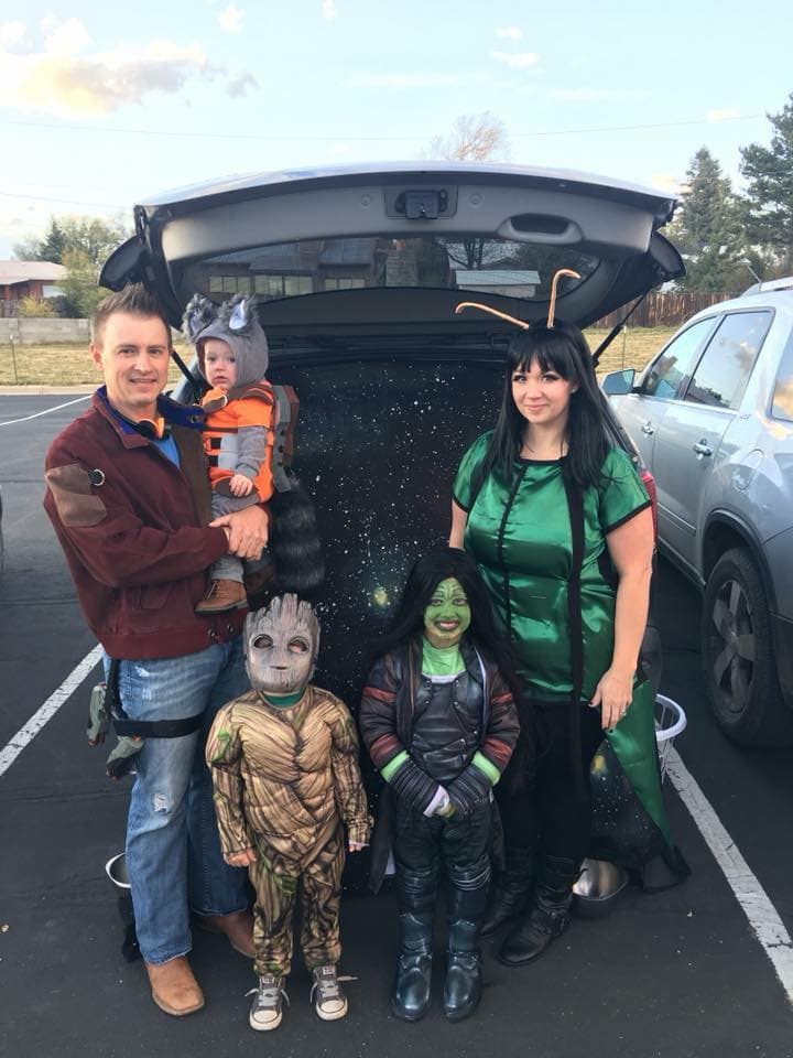 Family wearing Guardians of the Galaxy Halloween costumes smiles at trunk or treat.