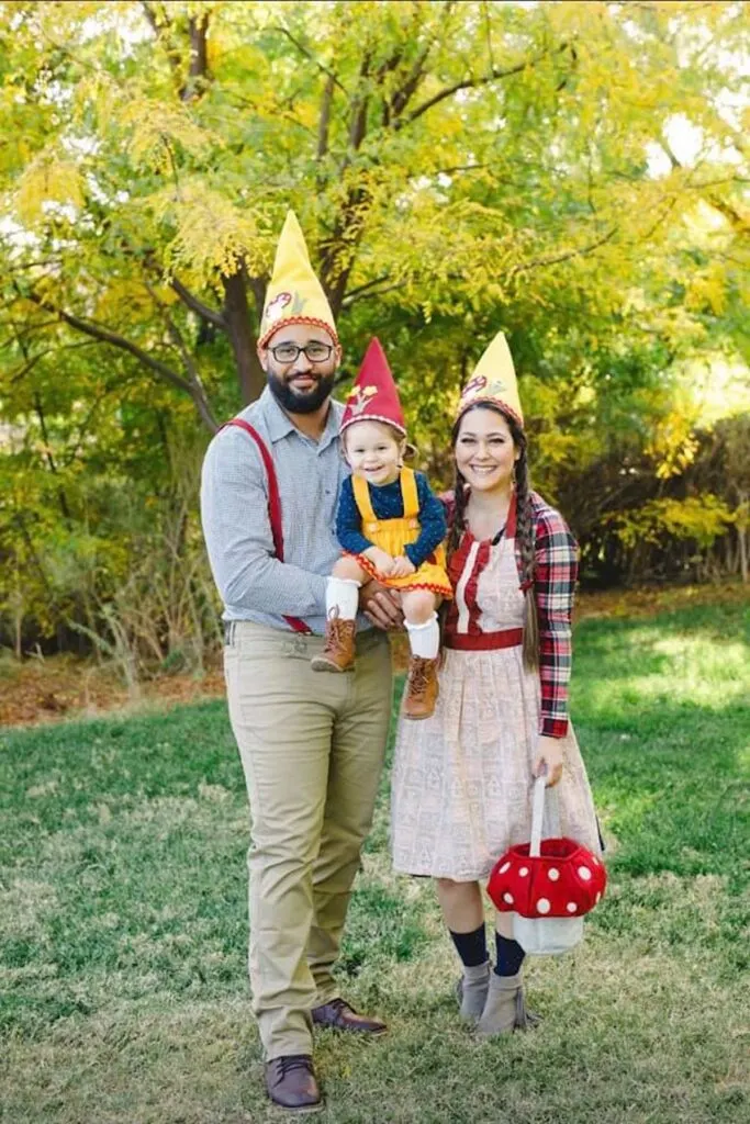 Family wearing gnome costumes stands in grass area and smiles.