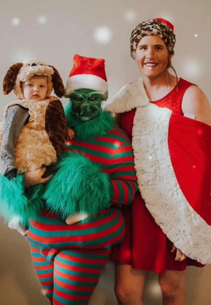 Family wearing character costumes from The Grinch smile for picture.