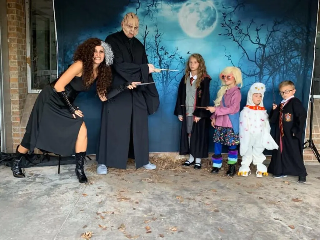 Family wearing Harry Potter costumes poses in front of photo backdrop.