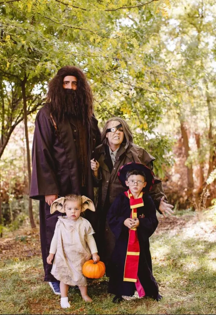 Family wearing Harry Potter costumes poses in front of trees.