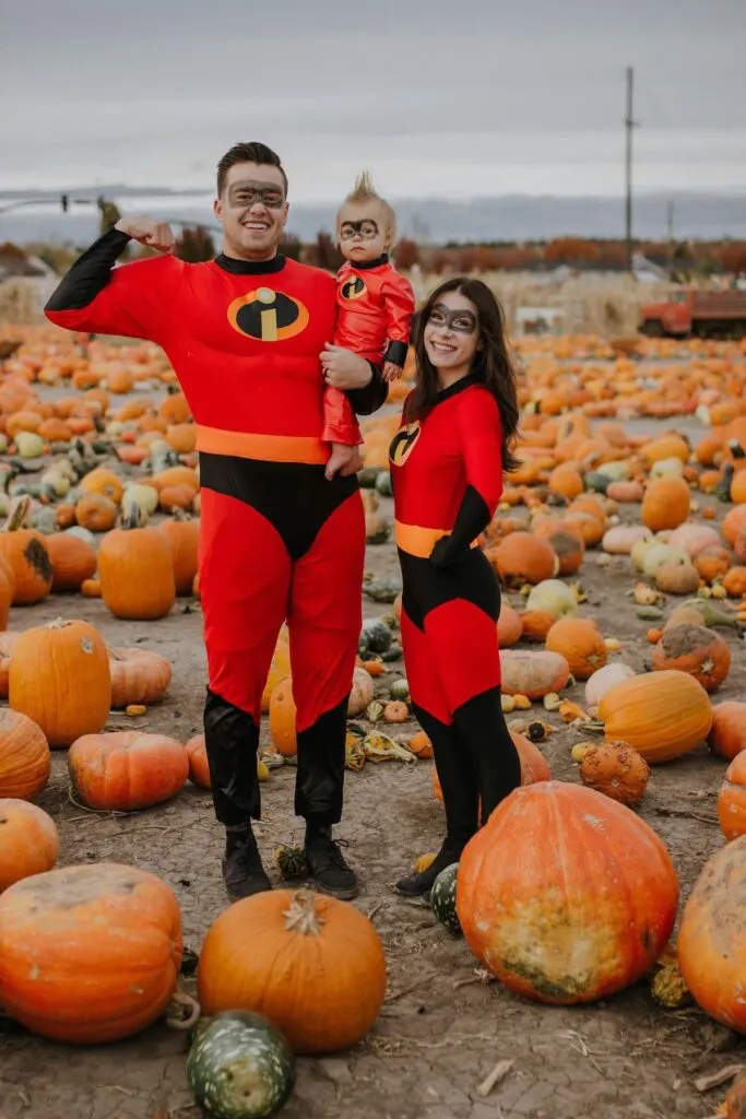 Family wearing Incredibles costumes poses in pumpkin patch.