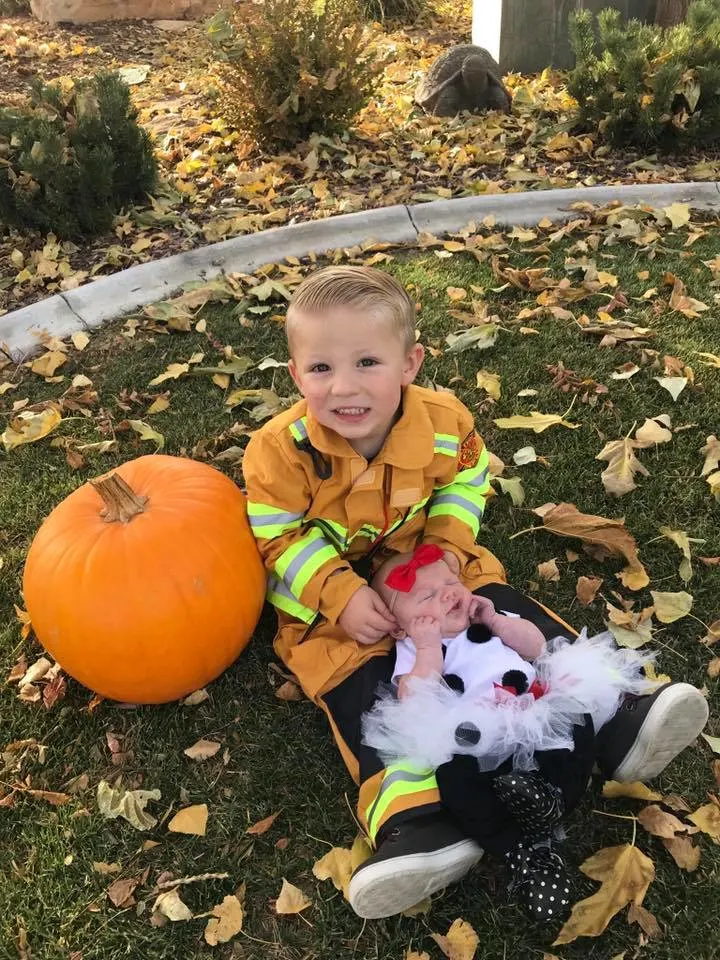 A boy in a firefighter costume with a baby girl in a dalmatian costume.