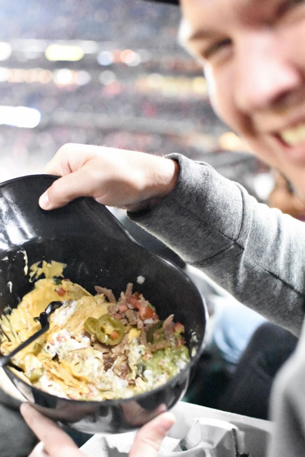 Man eating nachos from a baseball helmet at San Francisco baseball game.
