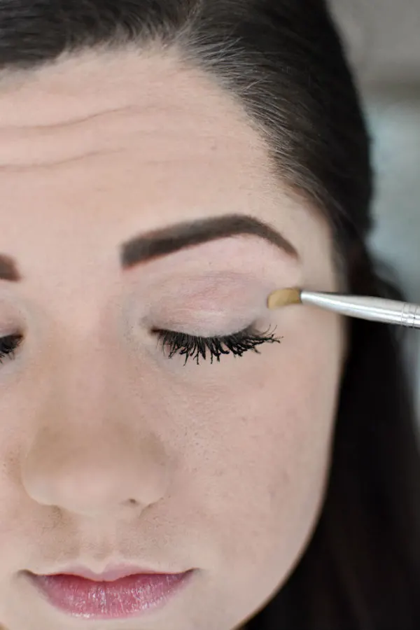Woman applying light eye shadow during an easy smokey eye tutorial 