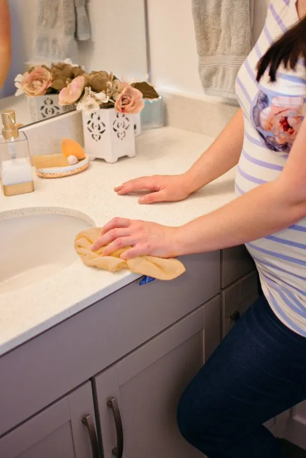 Woman wipes down bathroom counter during her home cleaning routine.