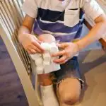 Boy holds a bag of frozen marshmallows on his bruised knee. 