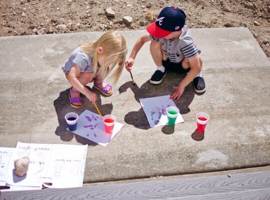 Boy and girl paint on the patio with colored water.