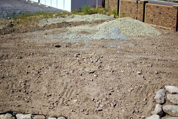 Large section of dirt and gravel in sloped backyard.