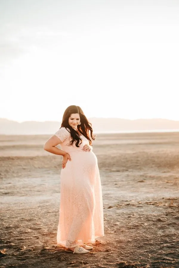 Woman wears a pink maternity dress for photo shoot.