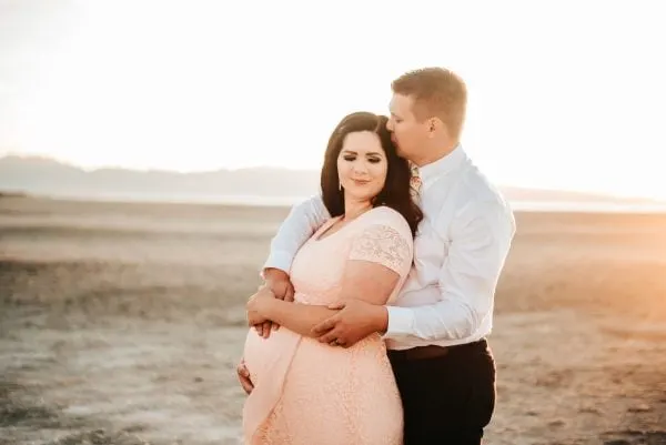 Couple poses for beach maternity pictures.