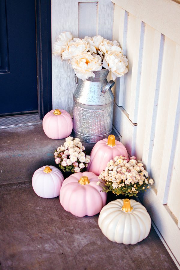 Pink pumpkins and mums on front next to tin milk jug with white faux flowers. 
