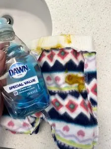 Woman holds Dawn dish soap next to baby poop clothes.