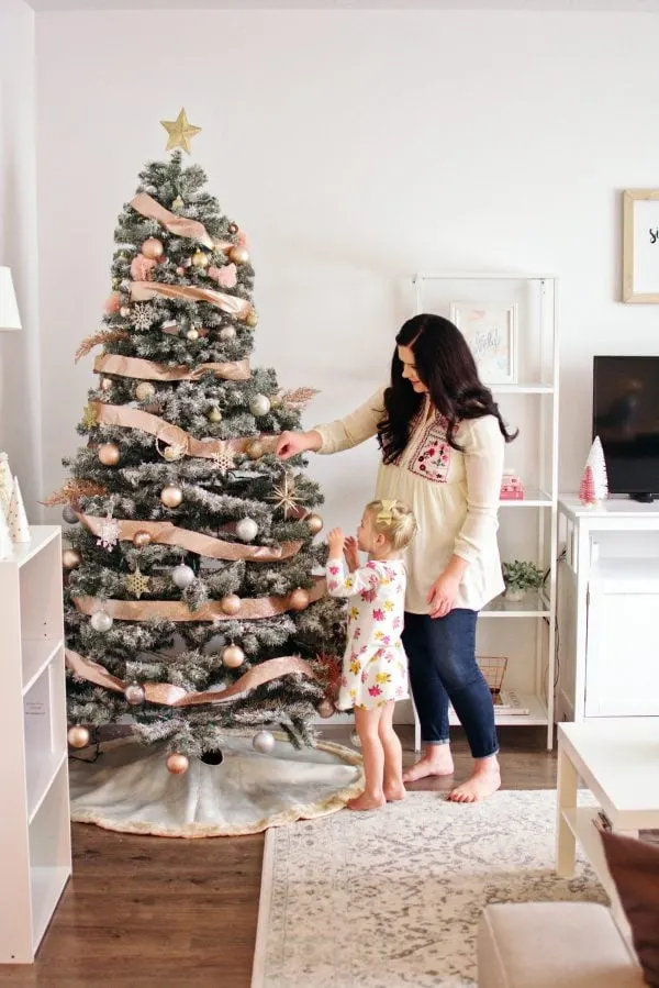 Mom and daughter decorate a Christmas tree as part of their family tradition.