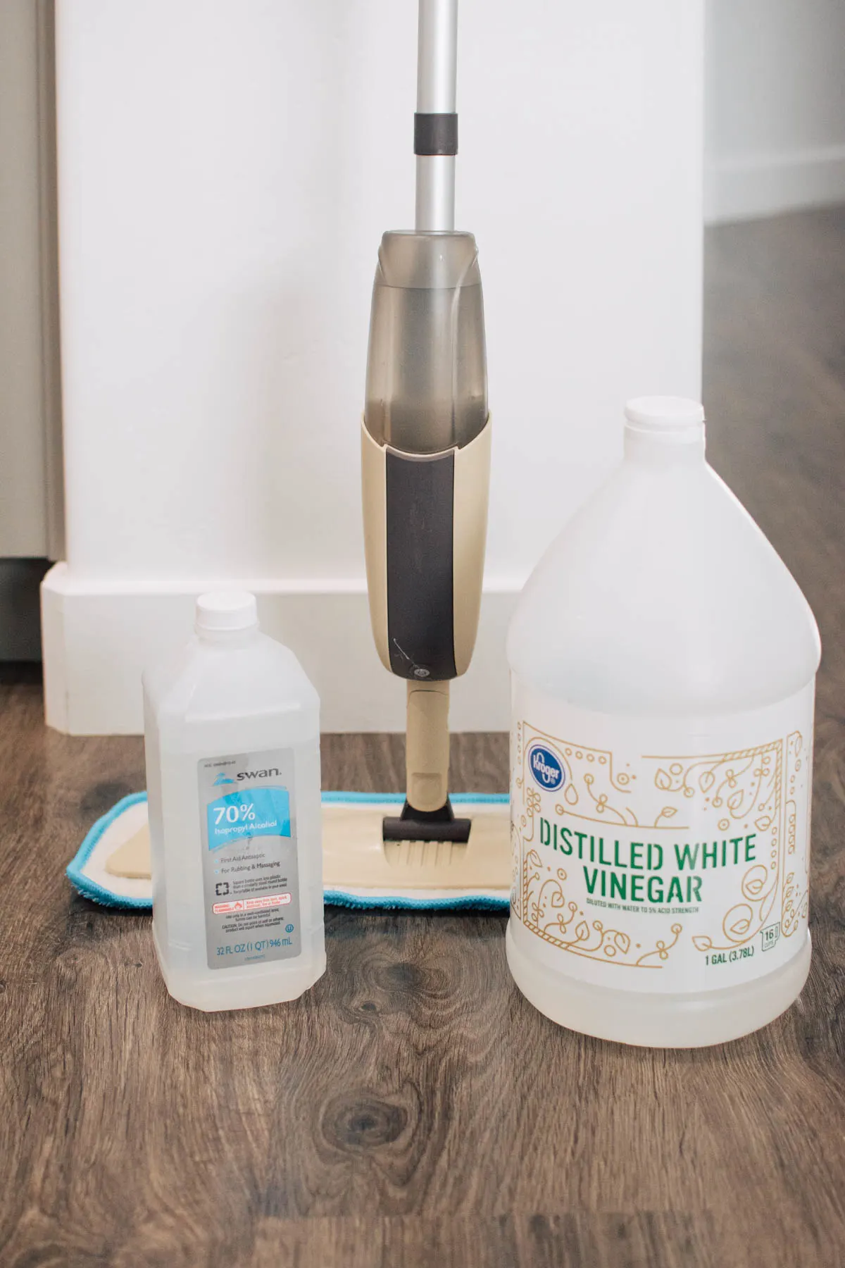 Ingredients to make a homemade laminate floor cleaner and a mom in front of white wall.