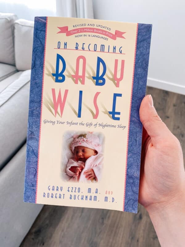 Mom holds Babywise book that she uses to sleep train her newborn.