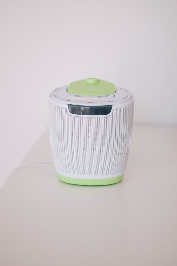 White noise machine with green accent colors on a table.
