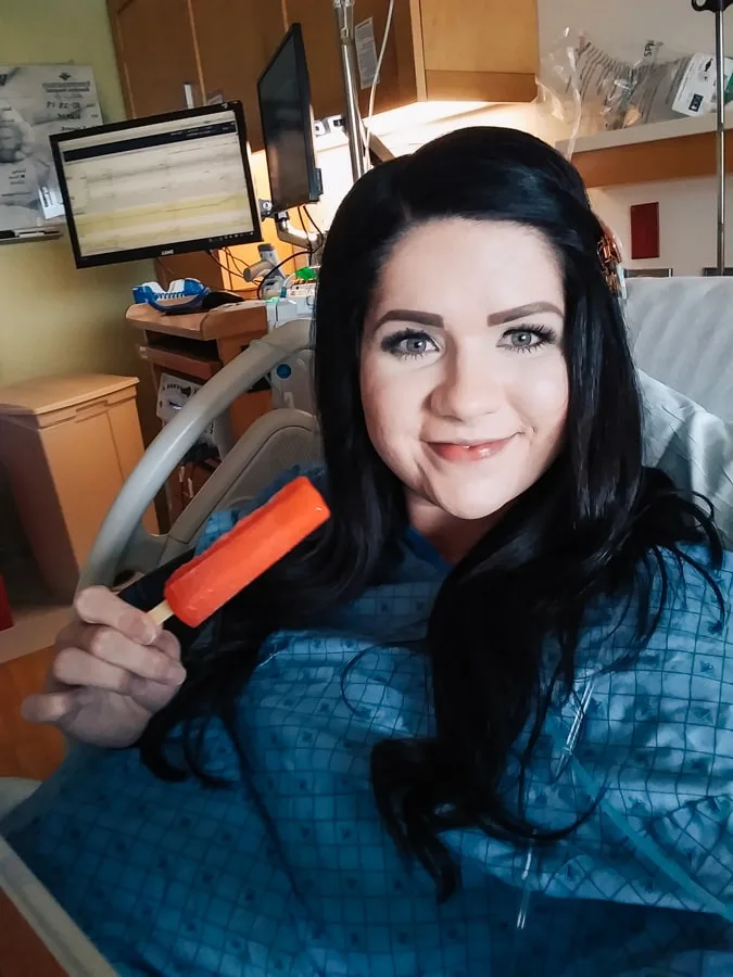 Woman holds up popsicle and smiles while she's being induced.