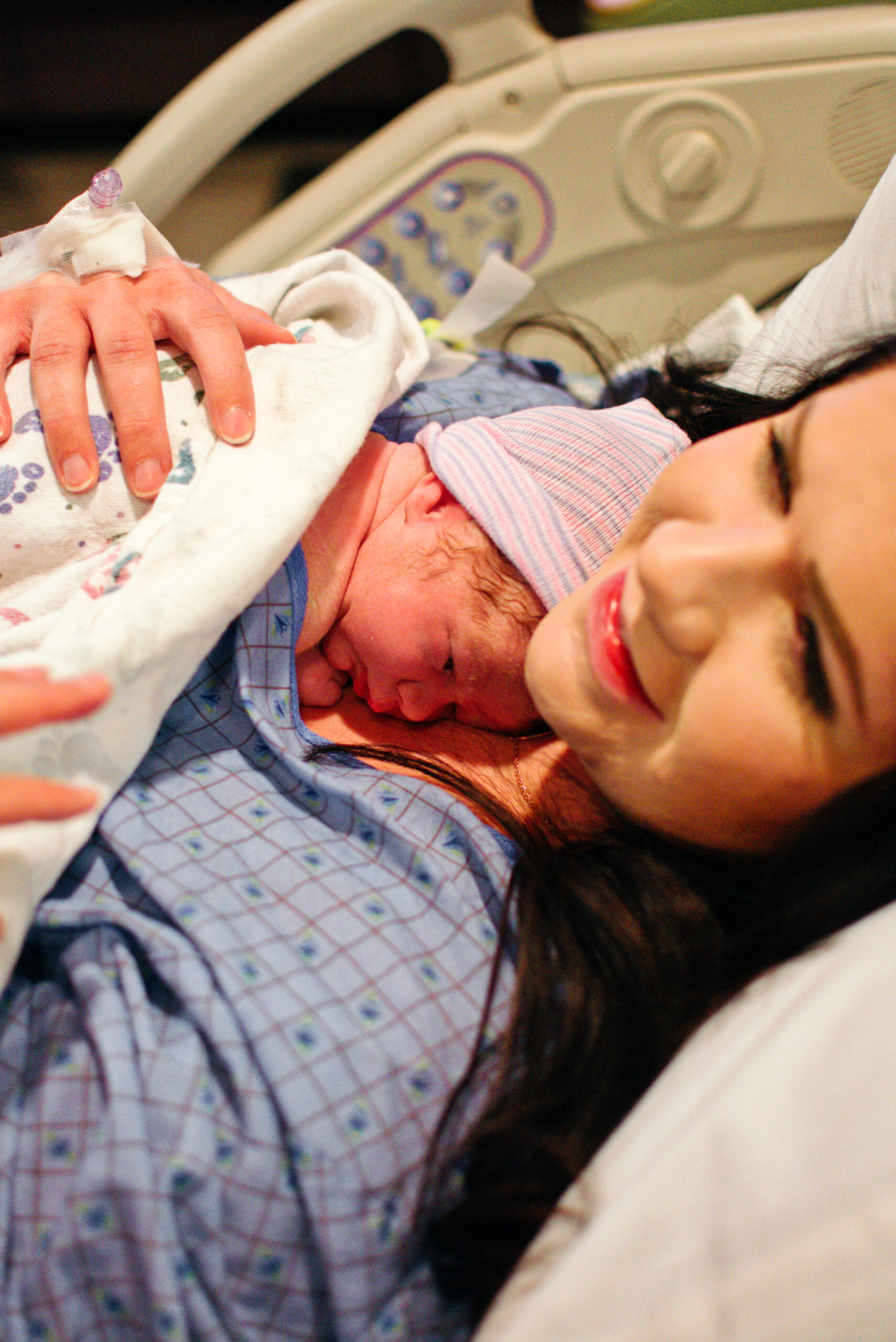 Woman holds newborn baby in hospital bed right after giving birth.