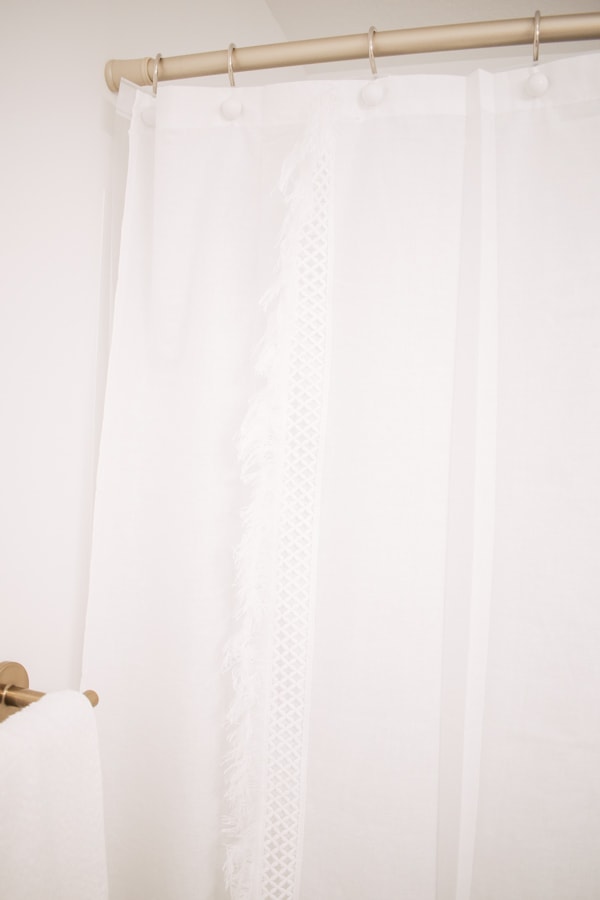 White shower curtain hangs in a bathroom.