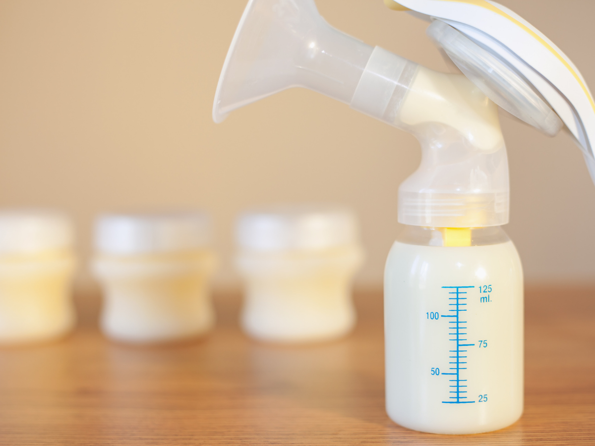 Breast pump on a table with milk in the bottle.