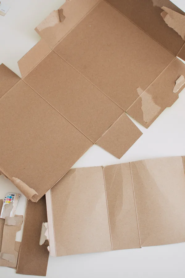 Two unfolded cardboard cartons, one with flaps cut off on white table.