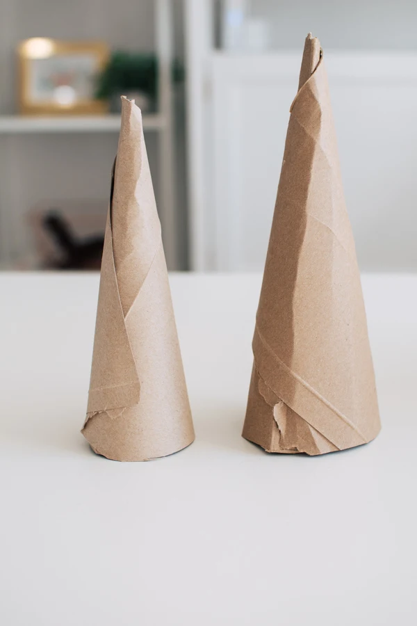 DIY Christmas tree cones made from cardboard cartons standing on white table.