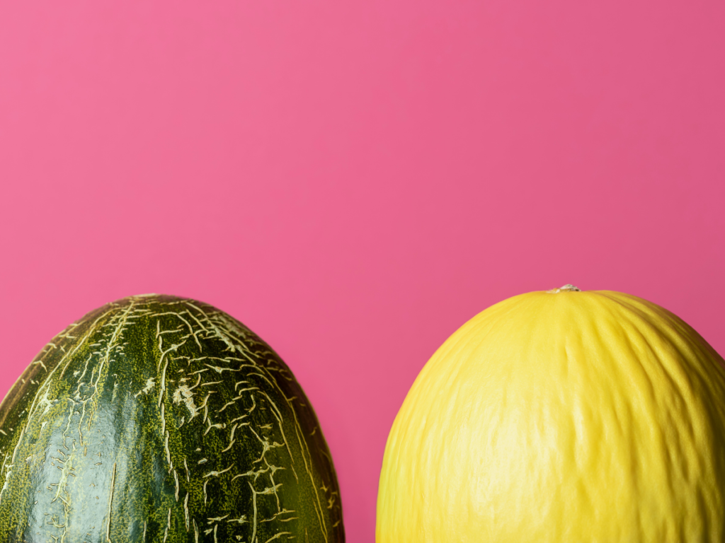 Two melons in front of a pink background.