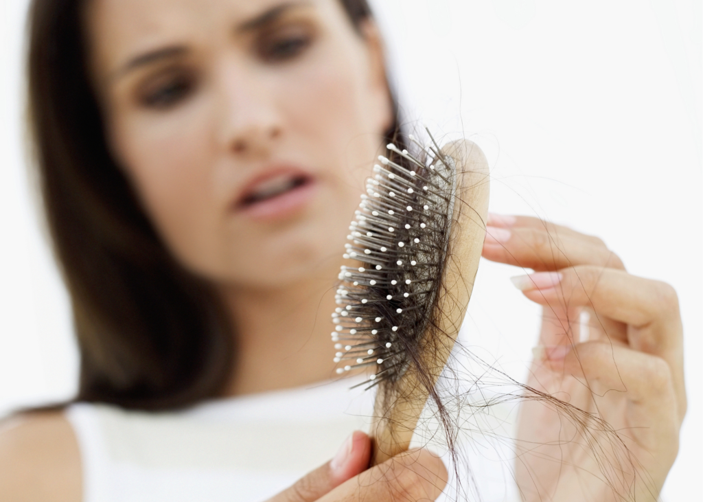 Woman holds brush filled with lost hair.