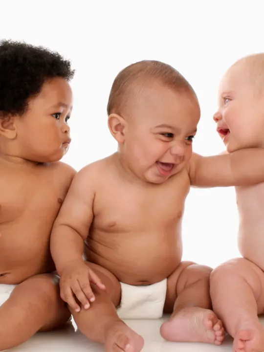 3 babies laugh and look at each other.