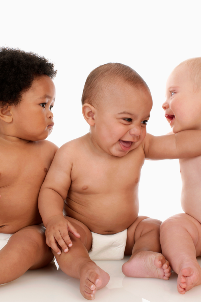 3 babies laugh and look at each other.