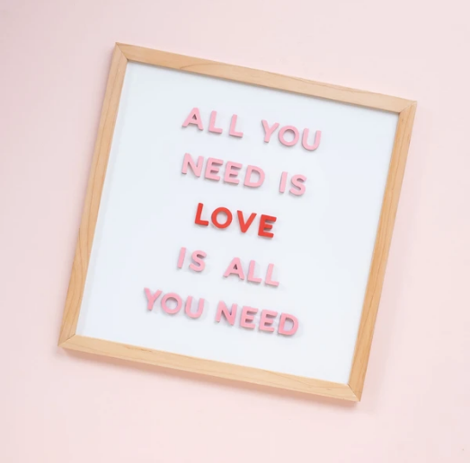 White magnetic letter board on a pink background.