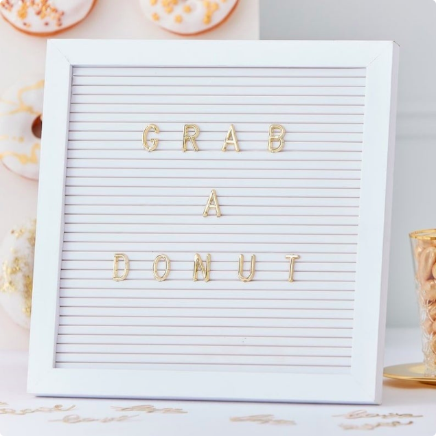 White letter board with gold letters.