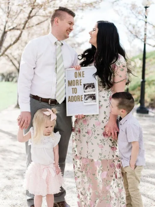 Family holds letter board baby announcement.