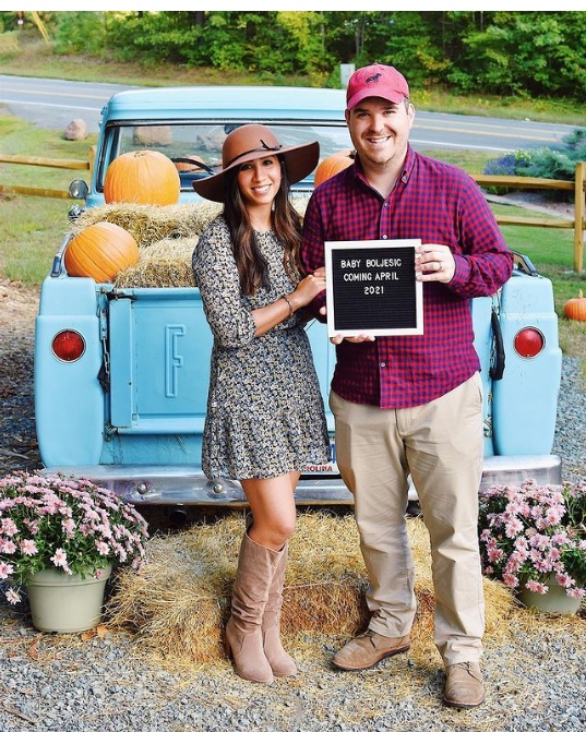 Couple holds up letter board baby announcement.