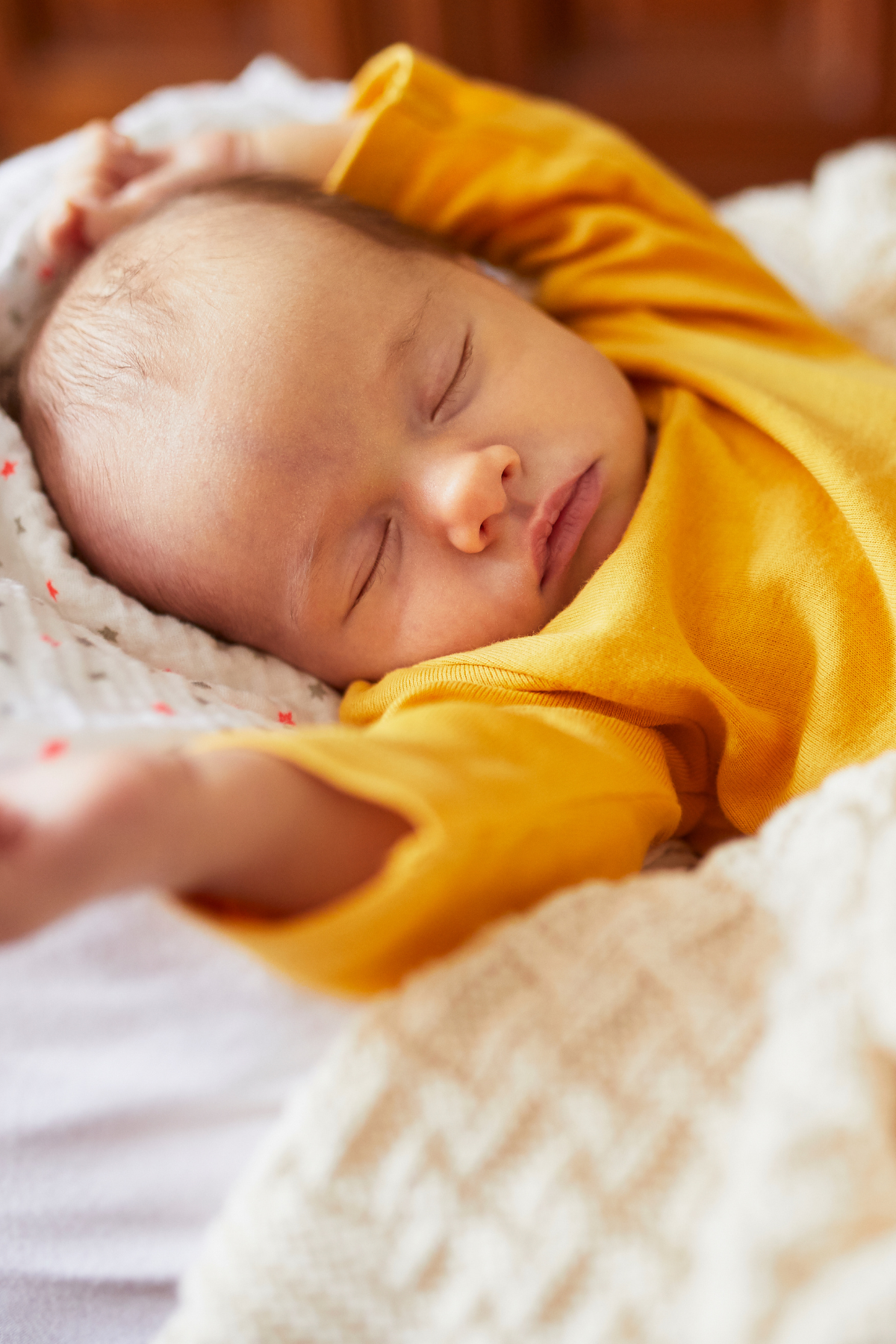Baby girl sleeps while wearing a yellow shirt.