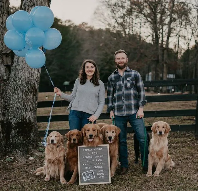 Husband, wife, and dogs stand next to letter board.