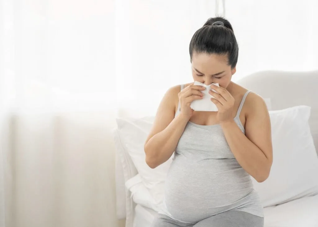 Sick pregnant woman blows her nose.